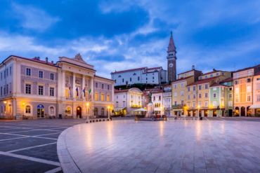 Twilight city square with old buildings and clock tower.