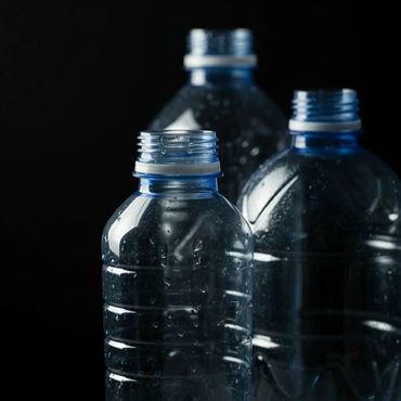 Close-up of three empty plastic water bottles with condensation against a black background.