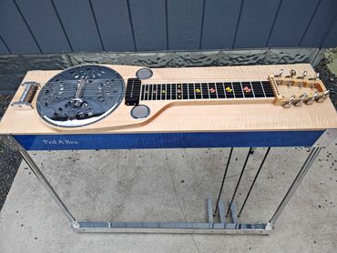 A custom pedal steel guitar with wooden body and metal legs.