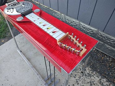 Red resonator lap steel guitar with cardinal bird fretboard inlays.
