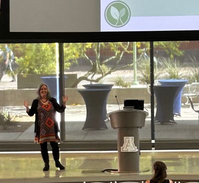 Woman presenting in front of an audience at a podium.