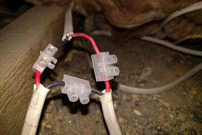 Unearthed wiring in loft void with exposed live contacts.