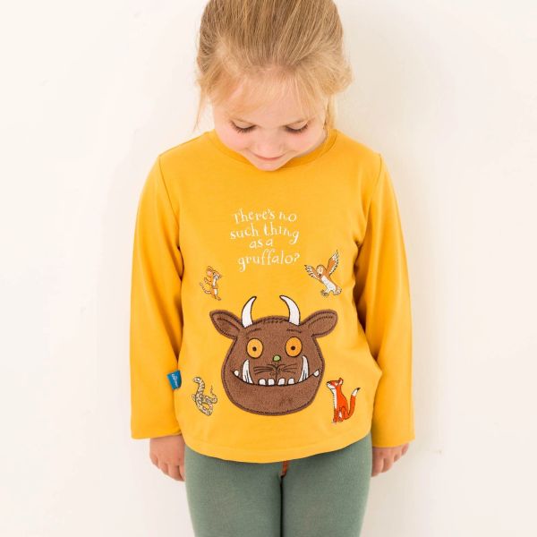 Child wearing a yellow Gruffalo-themed shirt, looking down.