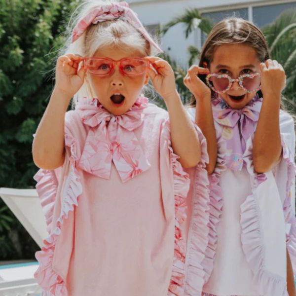Two surprised girls in colorful glasses and ruffled outfits.