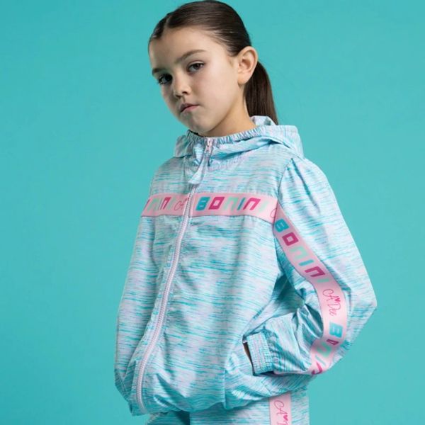 Young girl in a blue and pink tracksuit jacket.
