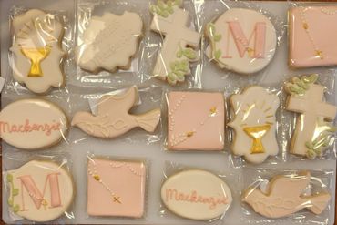 Decorated religious-themed cookies with names and symbols in pastel and gold.