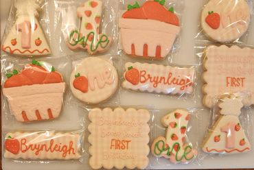 Decorated cookies for a first birthday with strawberries and pastel colors.