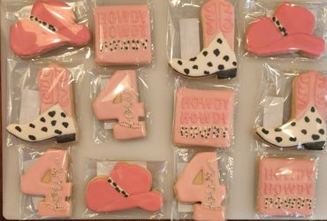 Pink cowboy-themed decorated cookies including boots, hats, and 'Howdy' squares.