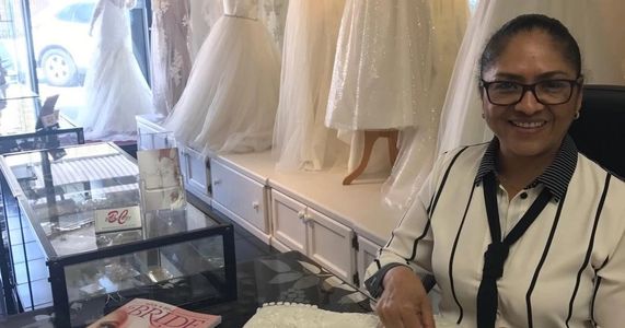 Owner and seamstress poses at her desk in BridalCity, showcasing her craft.