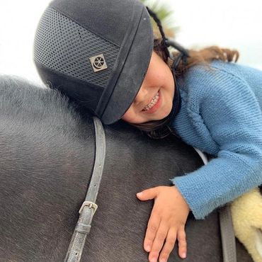 A small girl sleeping on horse