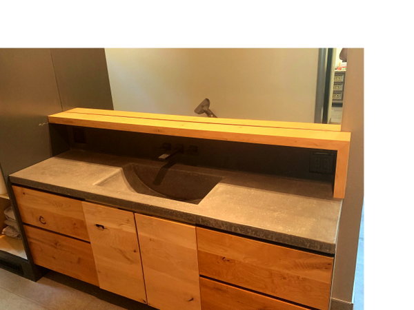 Modern bathroom sink with wooden cabinets and a concrete countertop.