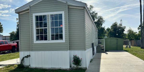 A gray and white mobile home with a red truck parked beside it.