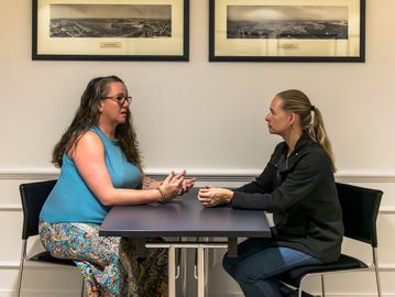 Two women engaged in a serious conversation at a table.