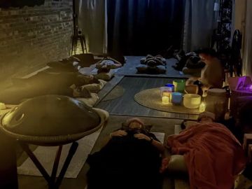 Group lying down in a dimly lit room with musical instruments.