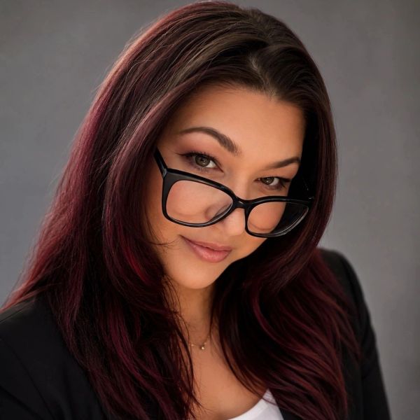 Woman with glasses and long dark hair looking confidently.