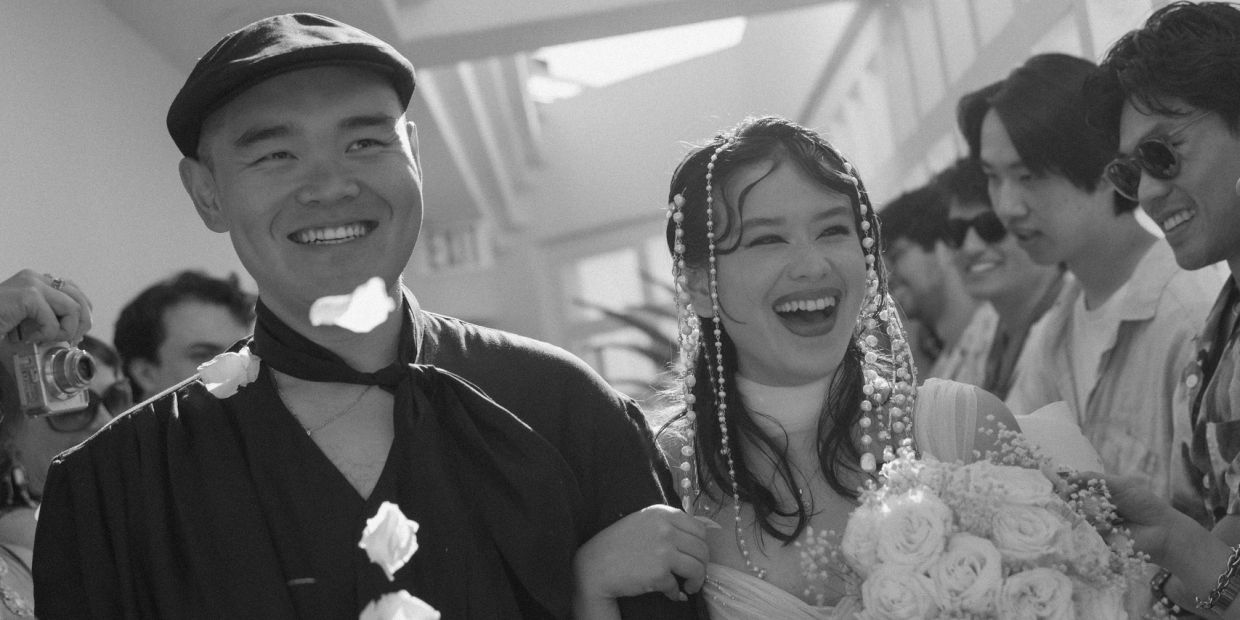 Joyful couple surrounded by friends in a black-and-white candid moment in Laguna Beach.