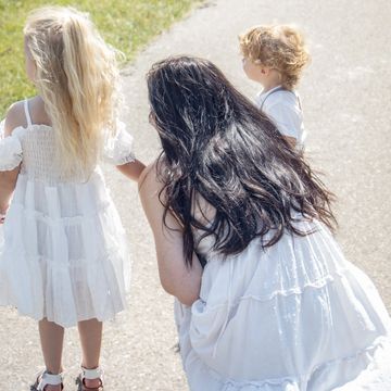 Woman and two children outdoors in white clothing.
