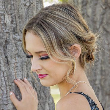 Woman with elegant makeup and hairstyle near tree.