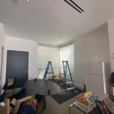 Room under renovation with ladders, tools, and furniture packed in boxes.