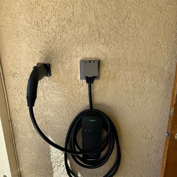 Electric vehicle charging station mounted on a textured beige exterior wall.
