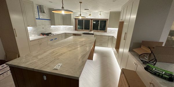 Modern kitchen under renovation with marble island and pendant lights.