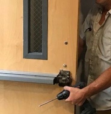 Locksmith installing panic bar with electric drill