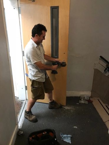 Locksmith with electric drill repairing door lock