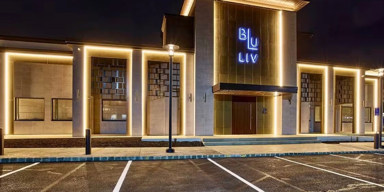 Modern building entrance with bright neon lights reading 'BLU LIV' at night.