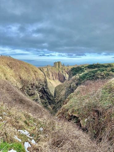 Ruins of a castle on a cliff under a cloudy sky.