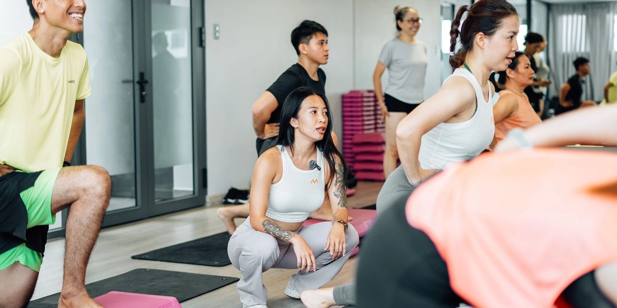 A group fitness class with participants stretching and exercising indoors.