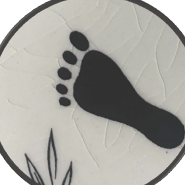A black footprint icon on a white circular background with leaf patterns.