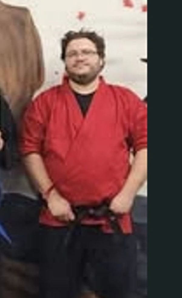 Man in red martial arts uniform with black belt.