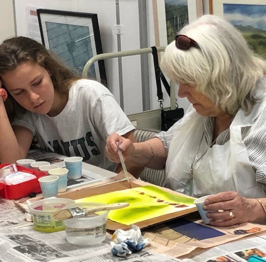 a participant getting help from a volunteer during art class