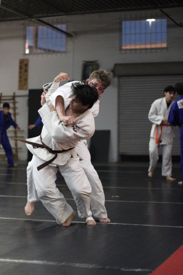 Two athletes practicing judo in white gi.