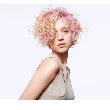 Soft curly pastel pink hair with luminous shine and a creative, textured finish.