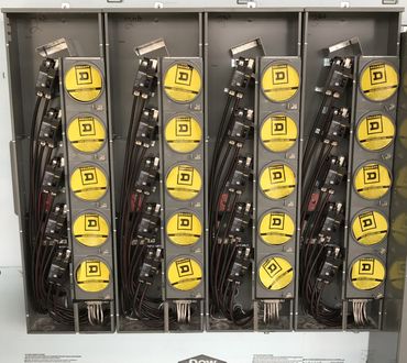 Four electrical meter panels with yellow Square D meters inside a metal box.