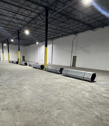 Large warehouse with bundled metal pipes neatly arranged on the floor.