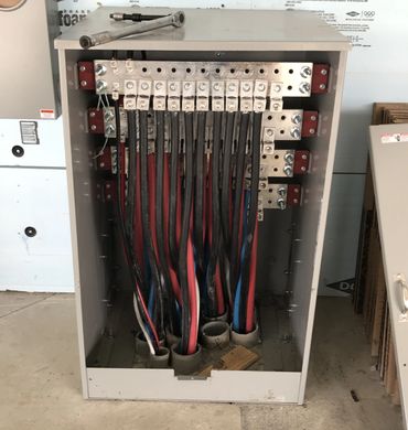 Open electrical panel with multiple colored cables connected to bus bars.