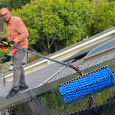 Person cleaning solar panels on a rooftop.