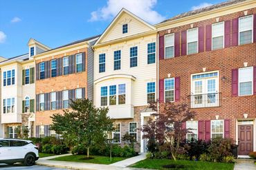 Row of colorful townhouses with manicured lawns under a clear blue sky.