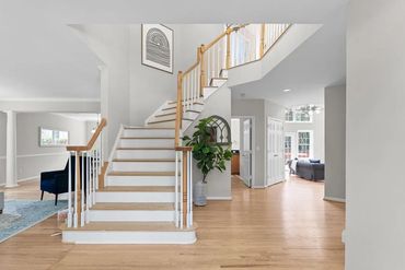 Bright, modern foyer with wooden staircase and light hardwood floors.