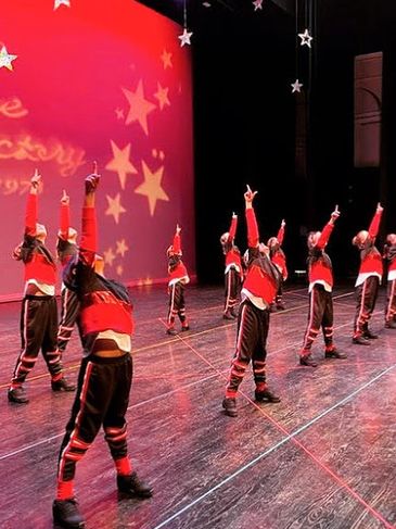 Group of teen dancers confidently performing hip hop on stage at recital in costume