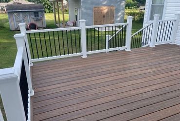 Backyard composite deck with white railings and wide steps built for easy access.