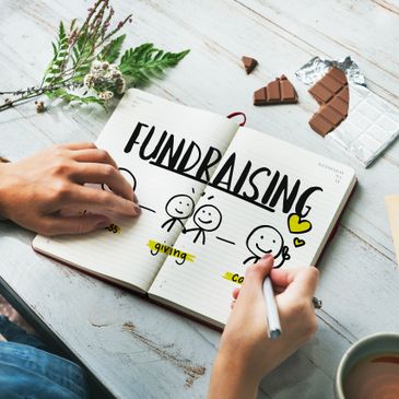 Person planning a fundraising event with doodles and notes in a notebook.