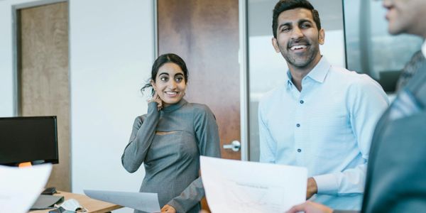 Colleagues sharing a light moment in a modern office meeting.