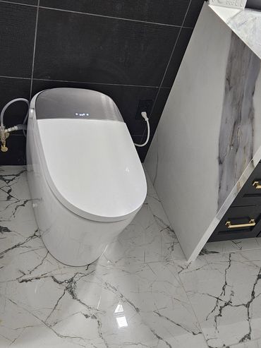 Modern white smart toilet in a bathroom with marble flooring and black textured wall.
