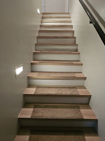 Wooden stairs with beige carpet runners and wall lights.