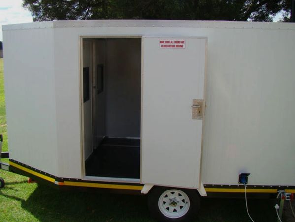 White mobile unit with an open door on grass.