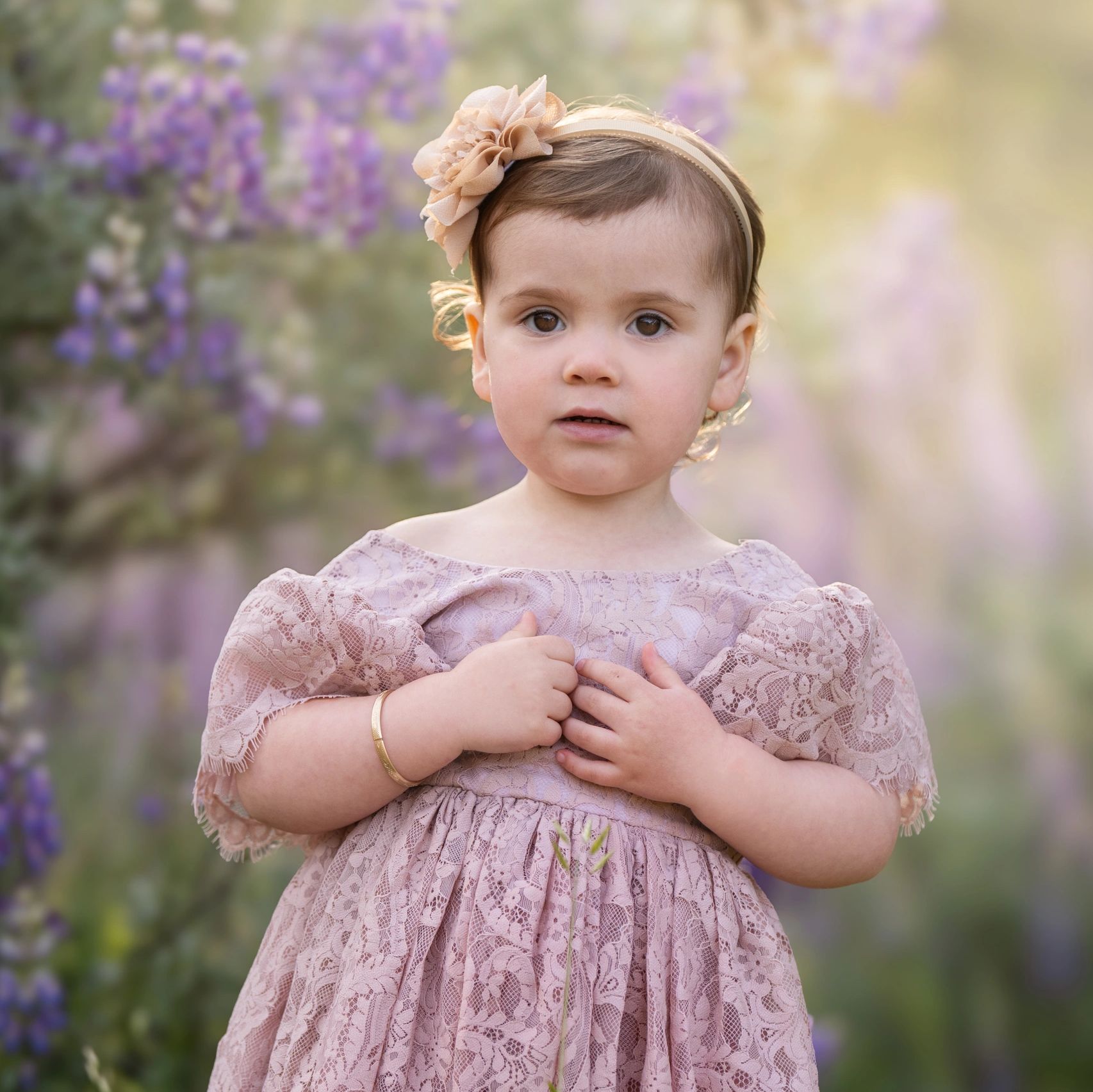 Toddler girl in lace dress standing in a field of lupine flowers