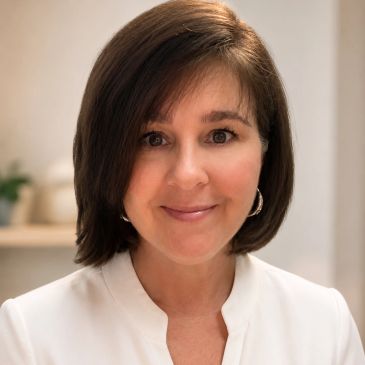 Smiling woman with straight brown hair and white top.